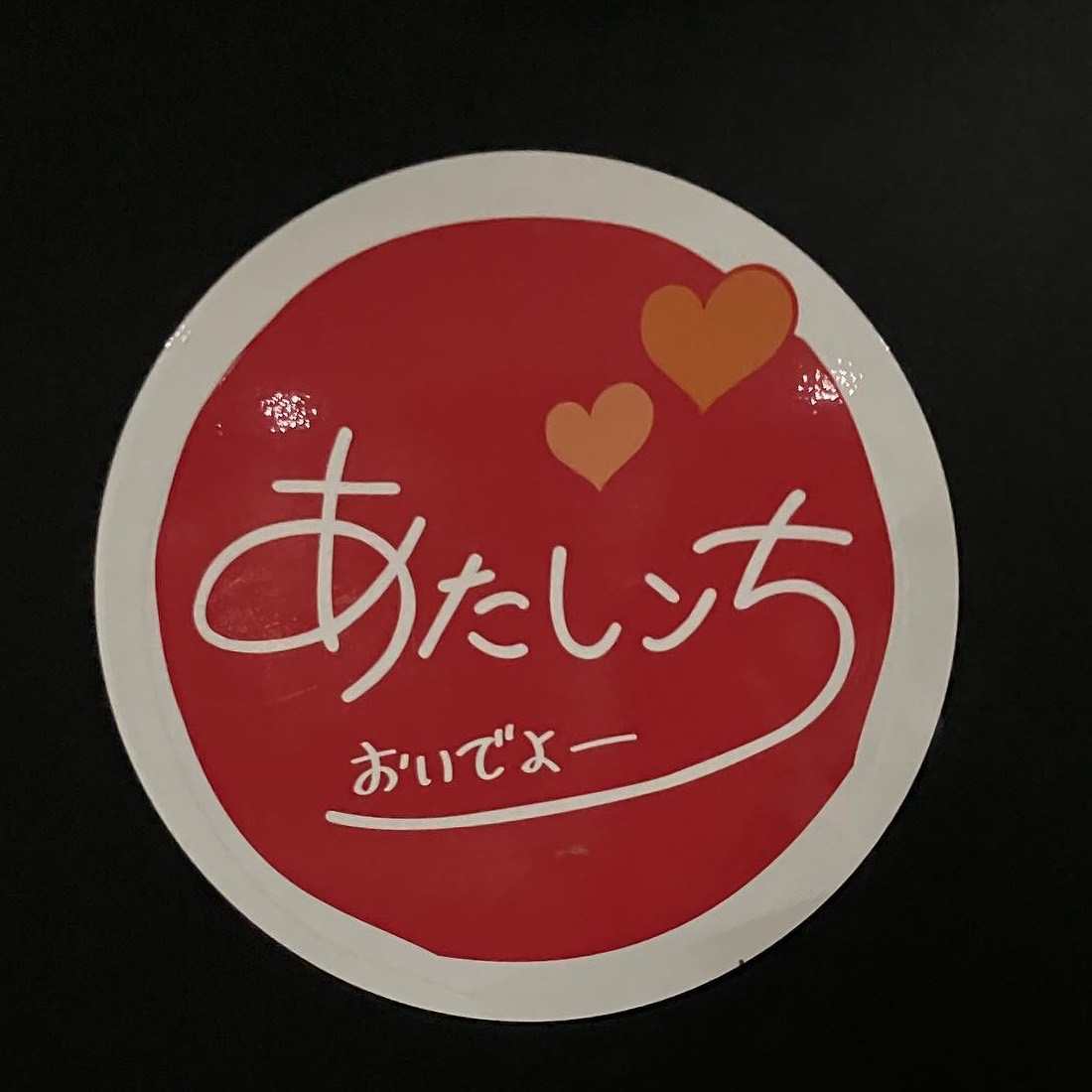 あたしンちのロゴ。赤い丸に白い手書きの「あたしンち」、オレンジのハート二つと「おいでよー」。