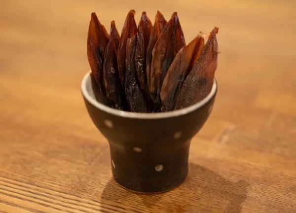 木のカウンターに置いた水玉の小鉢に、細長い乾きもののおつまみを立てて盛った一皿。